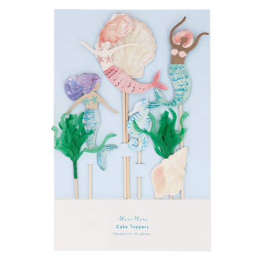 Set of mermaid-themed cake toppers with seashells and seaweed on a light blue background.